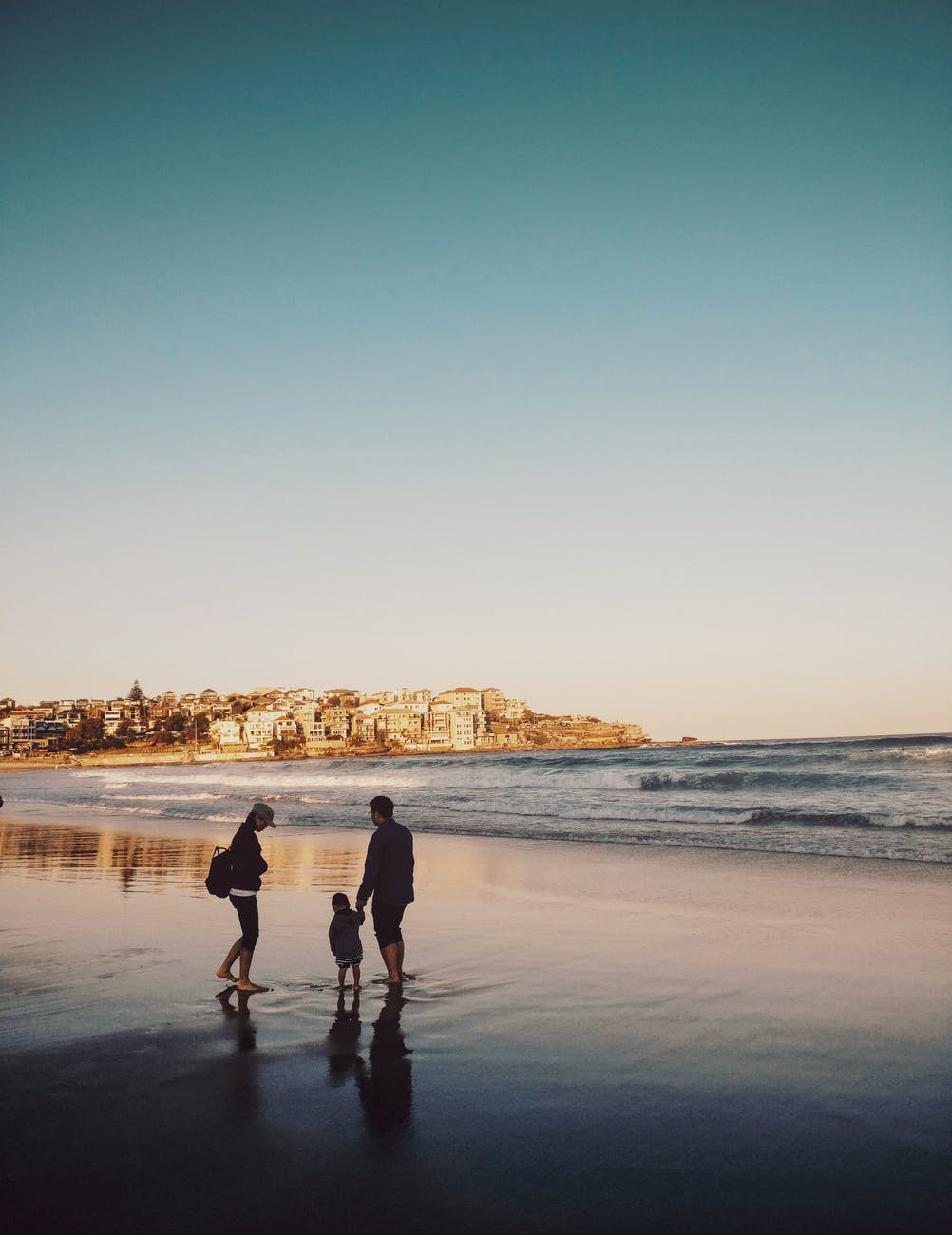Silhouette of parents with child on beach