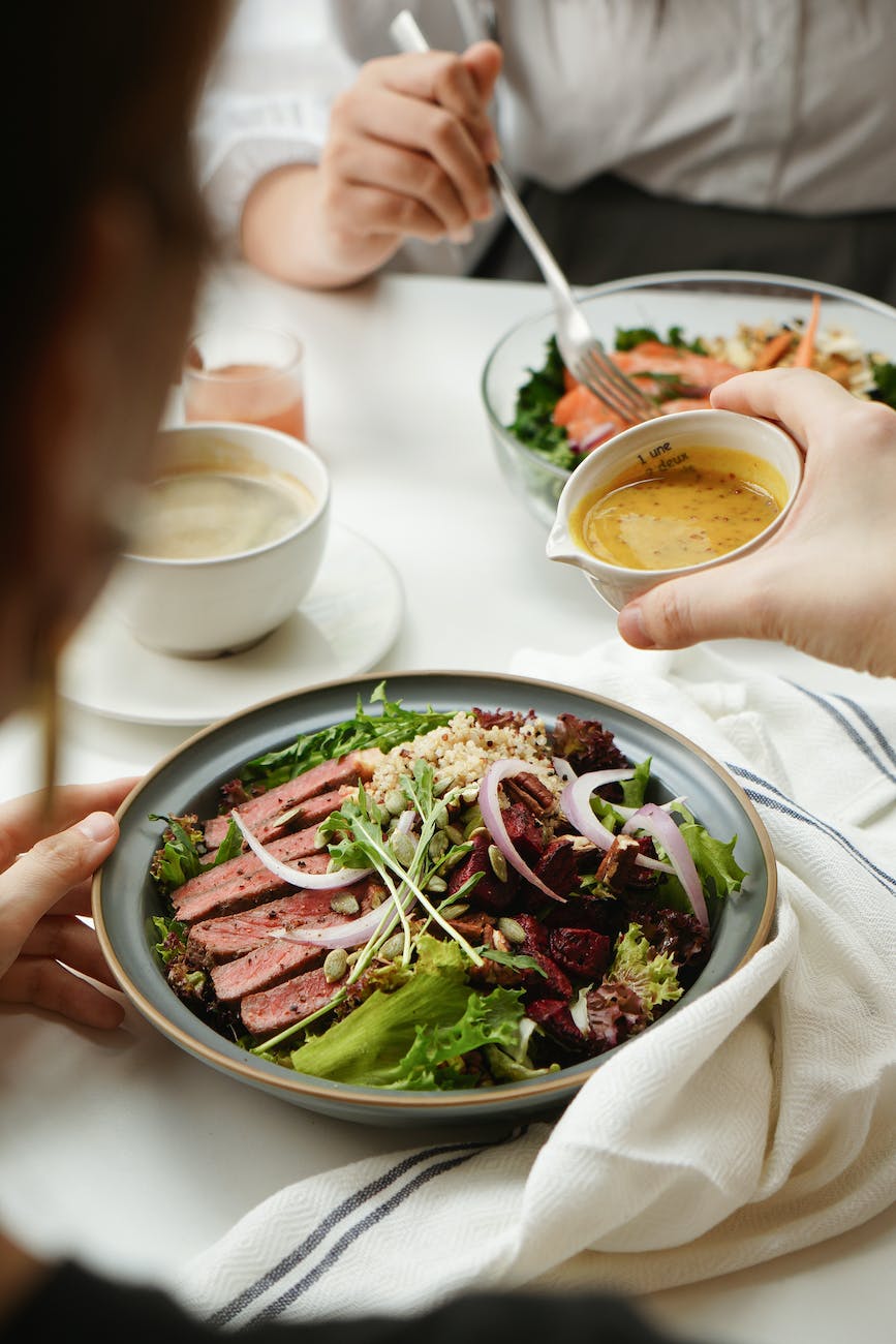 A table of food with 2 people eating